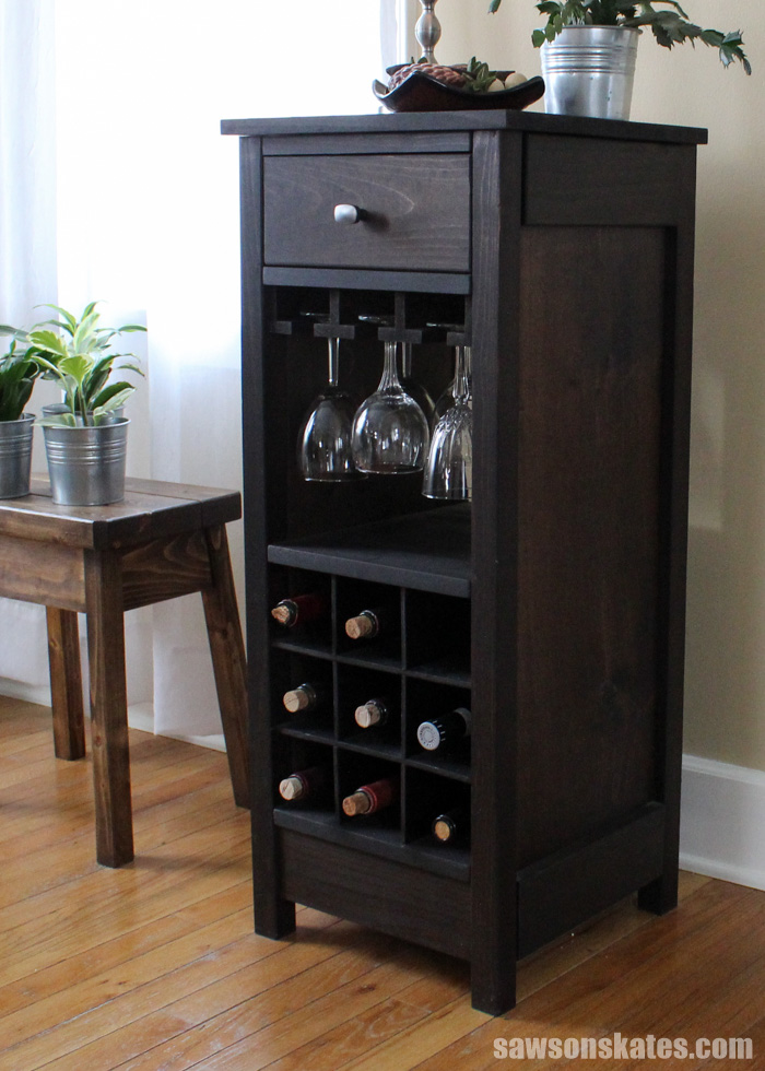 This wood DIY wine cabinet boasts nine spaces for wine bottle storage, three stemware holders for displaying up to 12 wine glasses and a drawer perfect for storing accessories like a bottle opener.