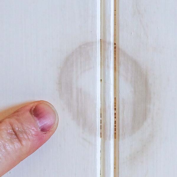 A wood knot bleeding through white paint