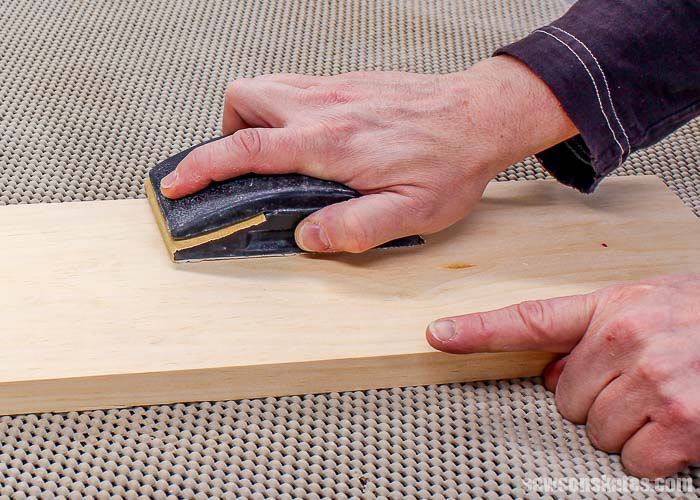 Sanding with the grain of the wood means sanding along the length of the board.