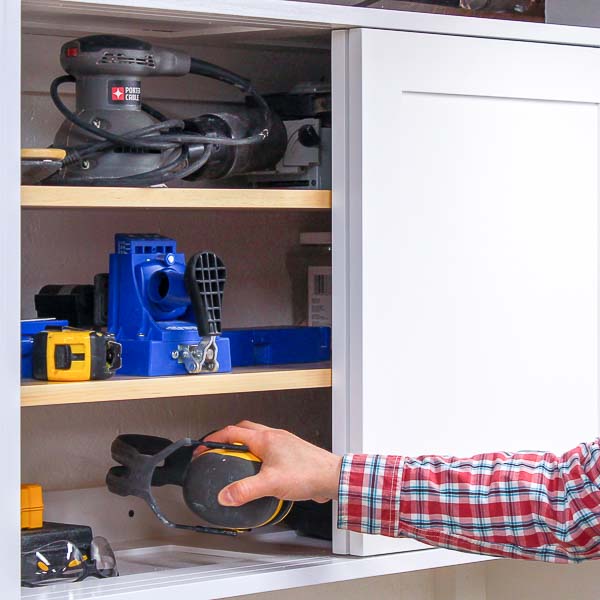 Putting a pair of ear muffs in the DIY workshop storage cabinet
