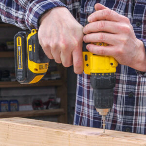 Using a drill to drive a screw into a piece of wood