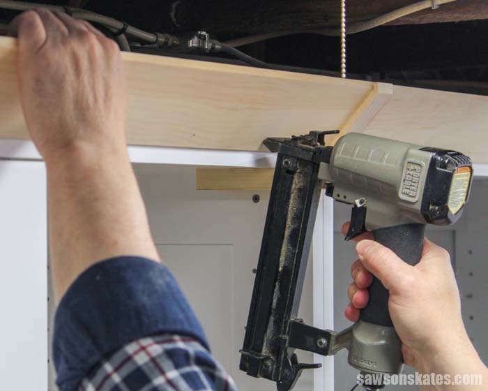 Using a nail gun to install Shaker style crown molding that was made with a table saw