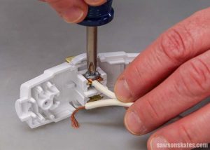 It's important to replace the wires on the correct screws when wiring a plug. Here a wire with ridges in the insulation is attached to the wider prong.