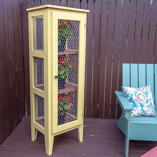 Outdoor plant stand filled with flowers next to an Adirondack chair
