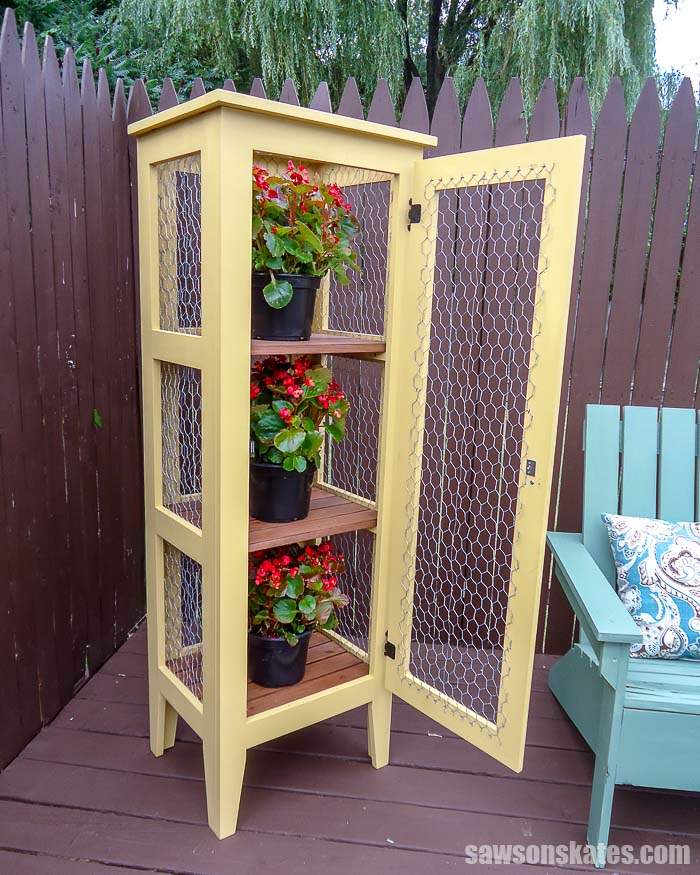 The door of this DIY outdoor plant stand is open showing the 3 tiers for displaying flowers