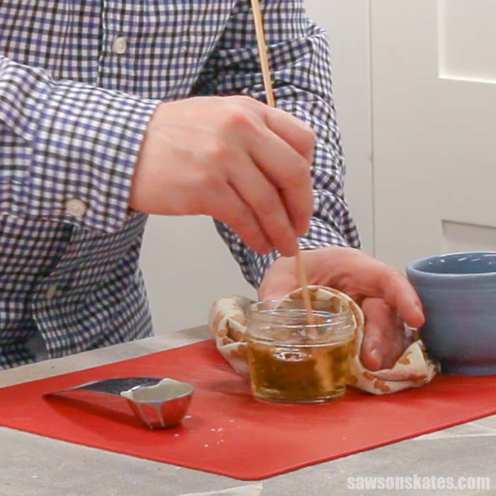 Stirring beeswax into coconut oil to make a DIY beeswax wood finish