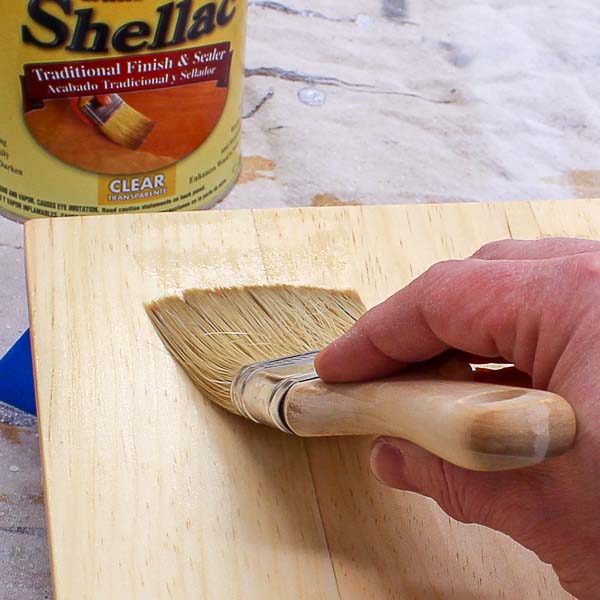 Applying shellac to a piece of wood with a brush