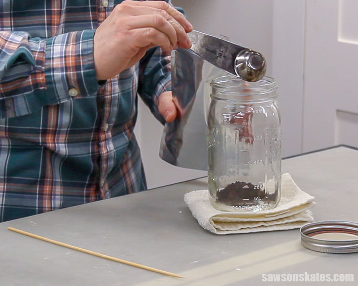 Pouring walnut hull powder into mason jar to make homemade black walnut stain
