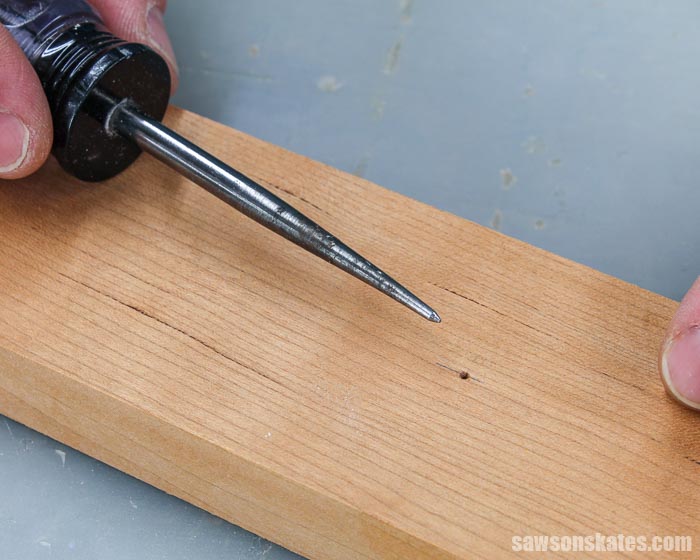 Using an awl to make a starting point to drill a hole in a DIY photo hanger