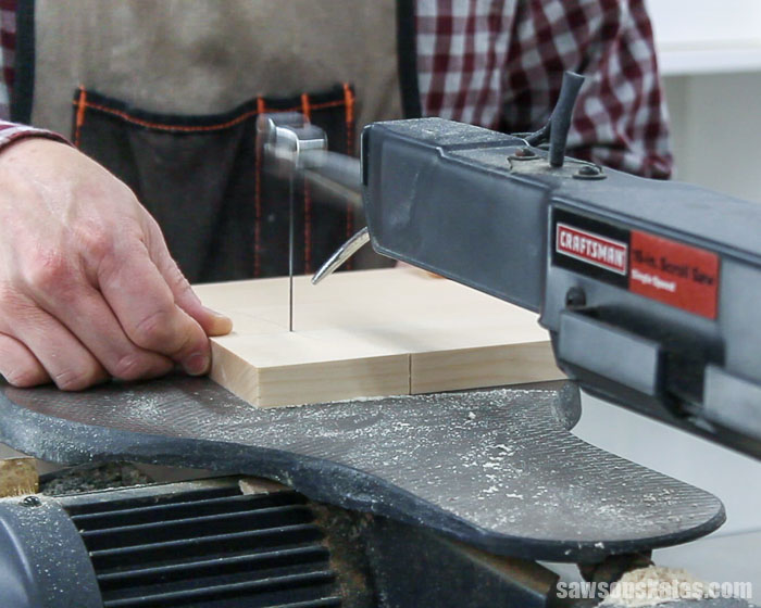 Using a scroll saw to cut out the curved detail on the side of a DIY display cabinet