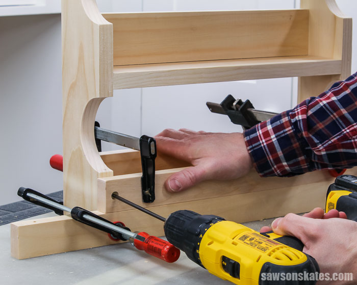 Using a drill to attach the bottom rail to a DIY spice shelf
