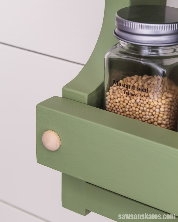 Close up of the rail that keeps spice jars in place on this DIY spice shelf