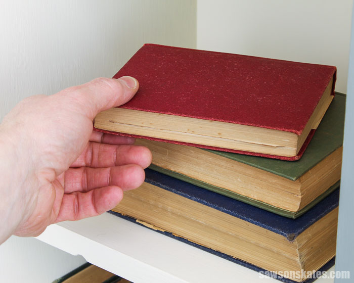 Hand removing a book from inside a DIY apothecary cabinet