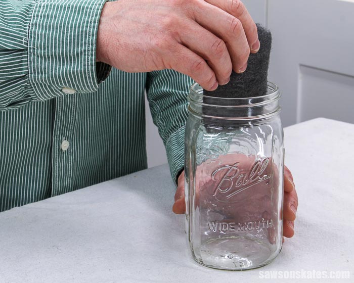 Placing a steel wool pad in a mason jar to make a steel wool and vinegar stain