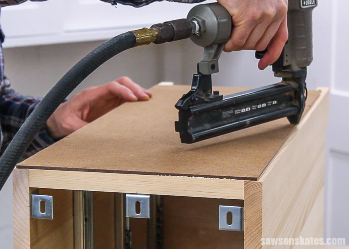 Brad nailer attaching back to a DIY nightstand with drawers