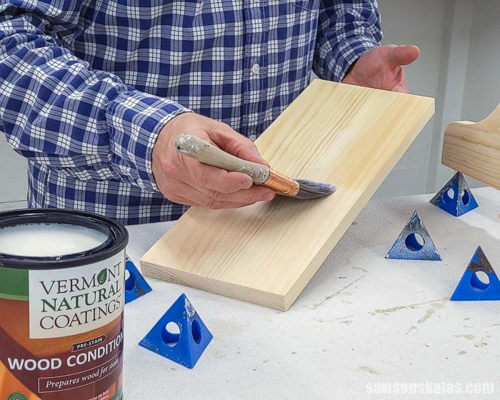 Using a brush to apply wood conditioner to the backside of a board before applying a stain and polyurethane in one