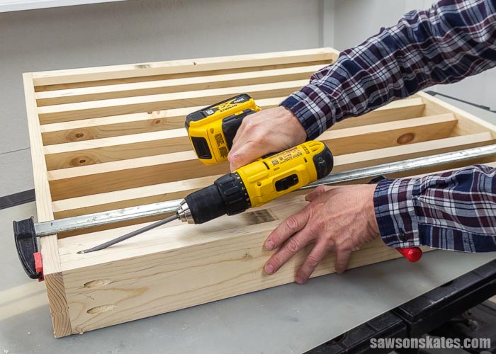 Using a drill to attach the bottom rail on a DIY paint storage rack