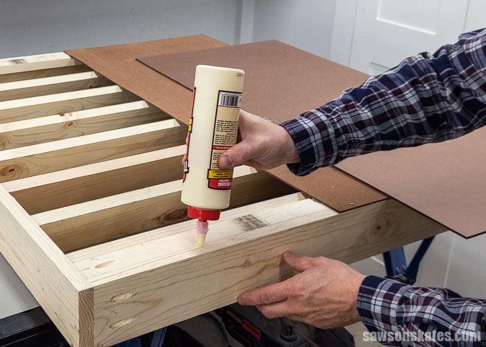 Applying glue to the back of a DIY wall-mounted paint rack