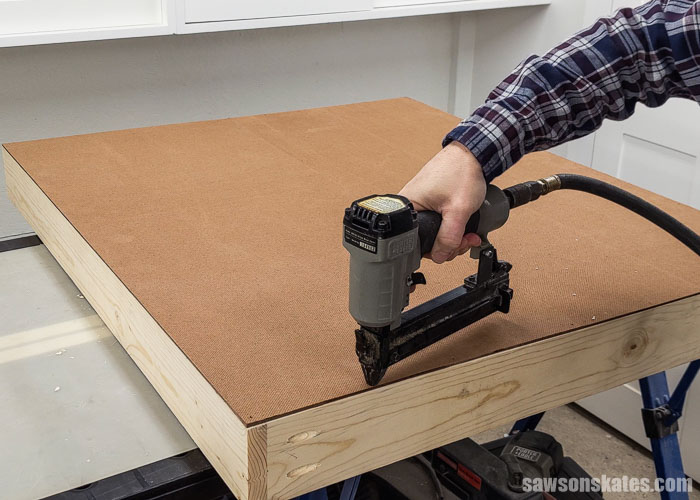 Using a brad nailer to attach the back on a DIY paint storage organizer