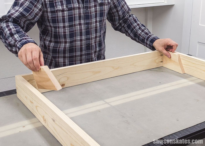 Placing pieces of scrap wood that will help position the top shelf on a wall-mounted paint display rack