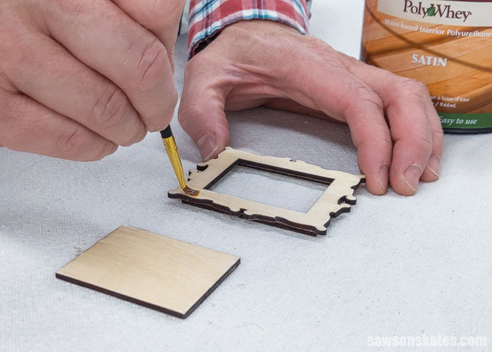 Using a paintbrush to apply polyurethane to a DIY Christmas picture frame ornament