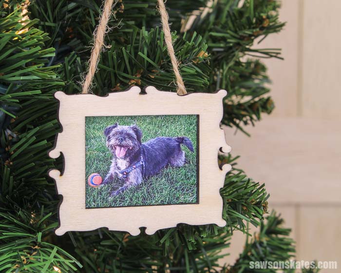 A DIY Christmas picture frame ornament hanging in a Christmas tree