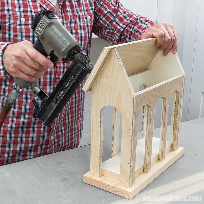 Using a brad nailer to attach the roof to a DIY holiday card display