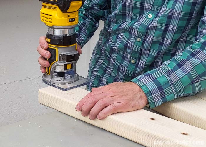 Using a handheld router to round over the cut edge of 2×4 used to build a DIY drill press stand