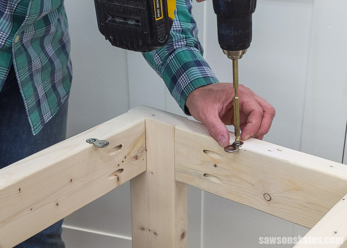 Using a screwdriver to attach a table top fastener to the base of a DIY drill press stand