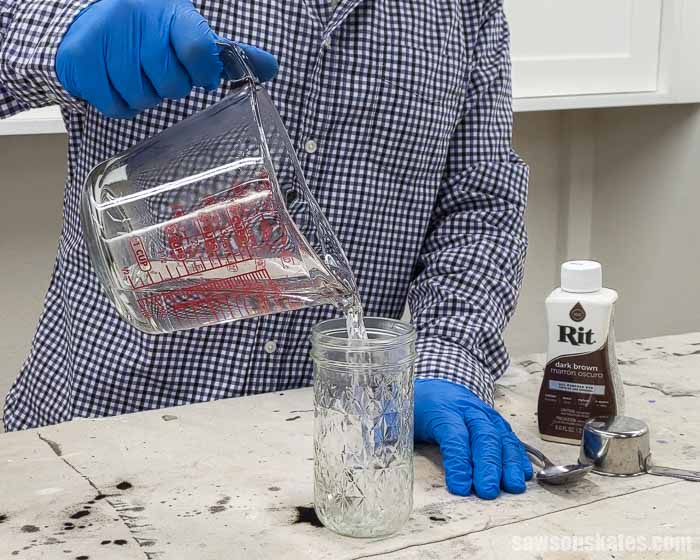 Pouring water in a mason jar to make a solution of Rit Dye to apply on wood