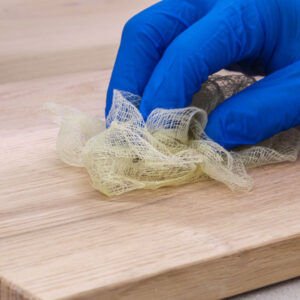 Using a tack cloth on a piece of wood to remove dust