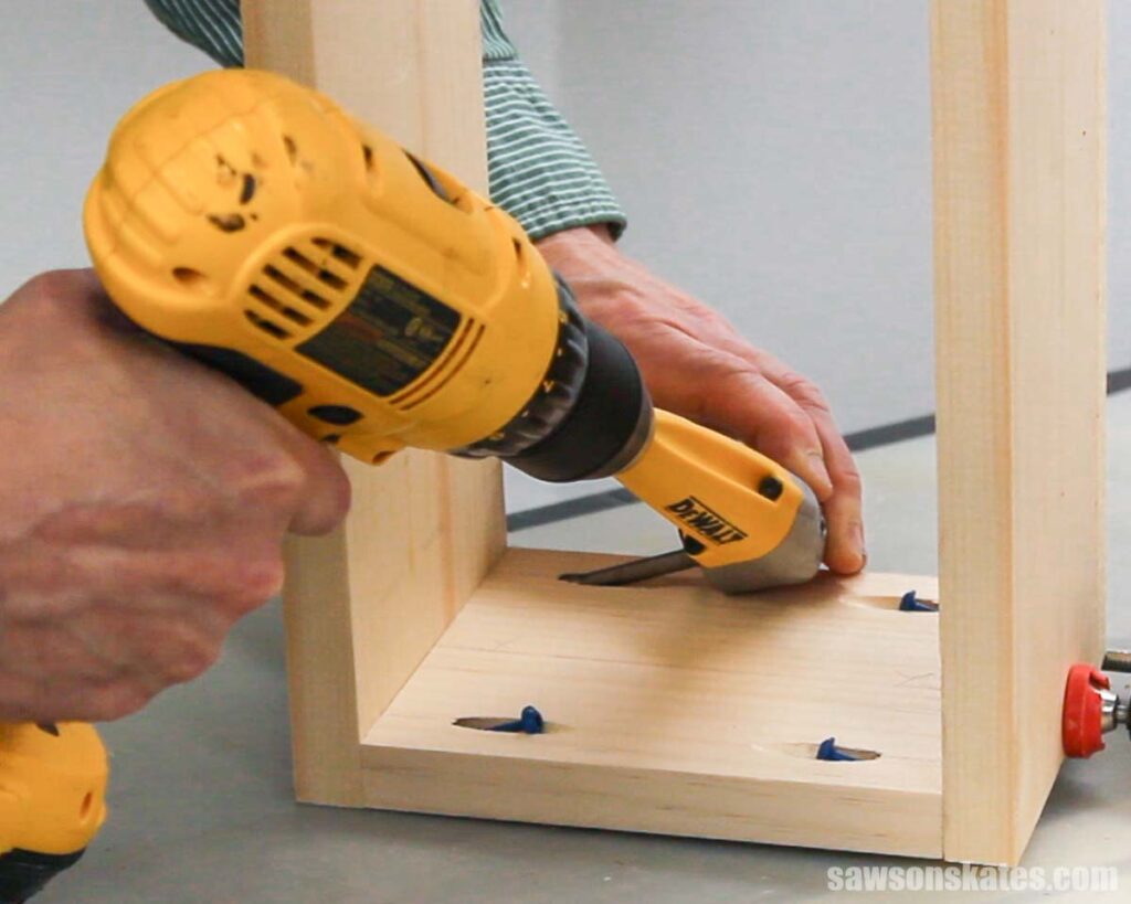 Using a drill to drive screws to assemble the sides of a box for a DIY wall-mounted planter