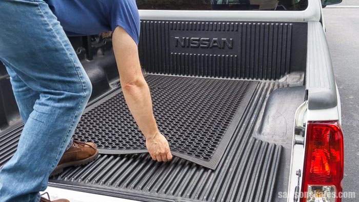 Placing a rubber mat in the bed of a truck before loading a DIY truck camper