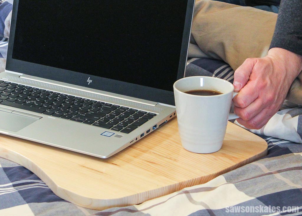 Hand placing a cup of coffee on a diy portable lap desk