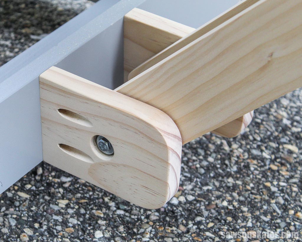 The folding arms of this DIY miter saw stand pivot on wooden anchors