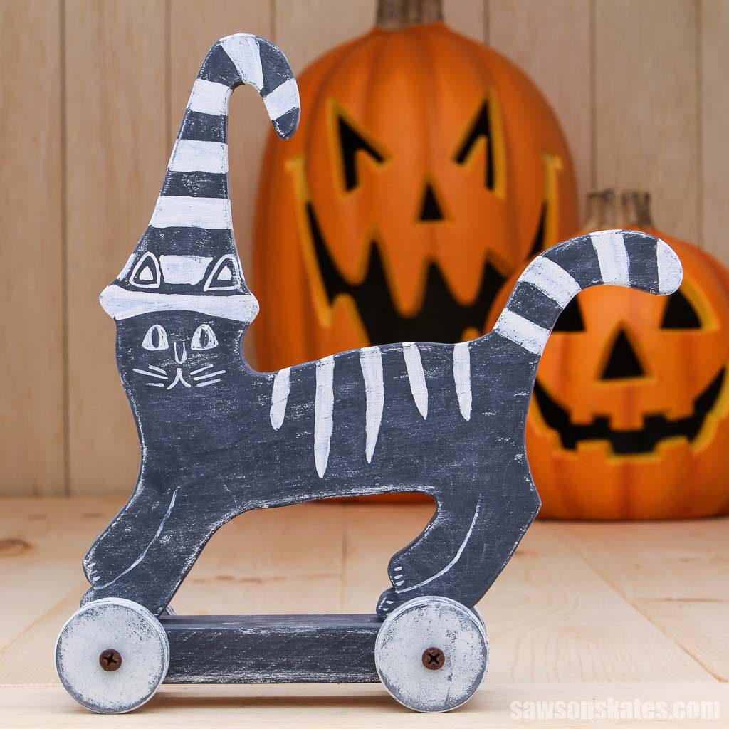 Homemade Halloween cat shelf sitter made with pieces of scrap wood, wooden wheels and paint