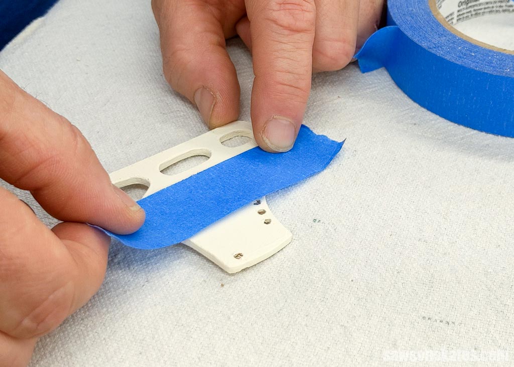 Applying painters tape before painting  the blade on a wood DIY ice skate Christmas ornament
