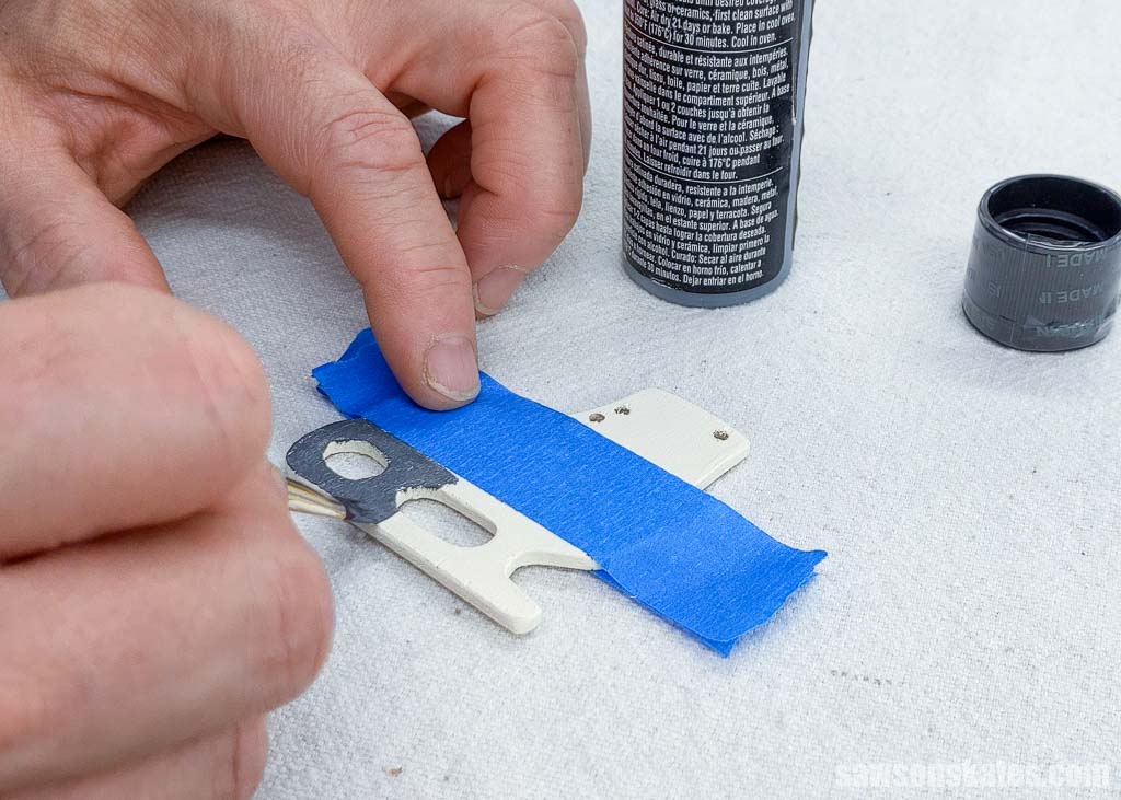Using a small brush to paint the blade on a wooden DIY ice skate ornament