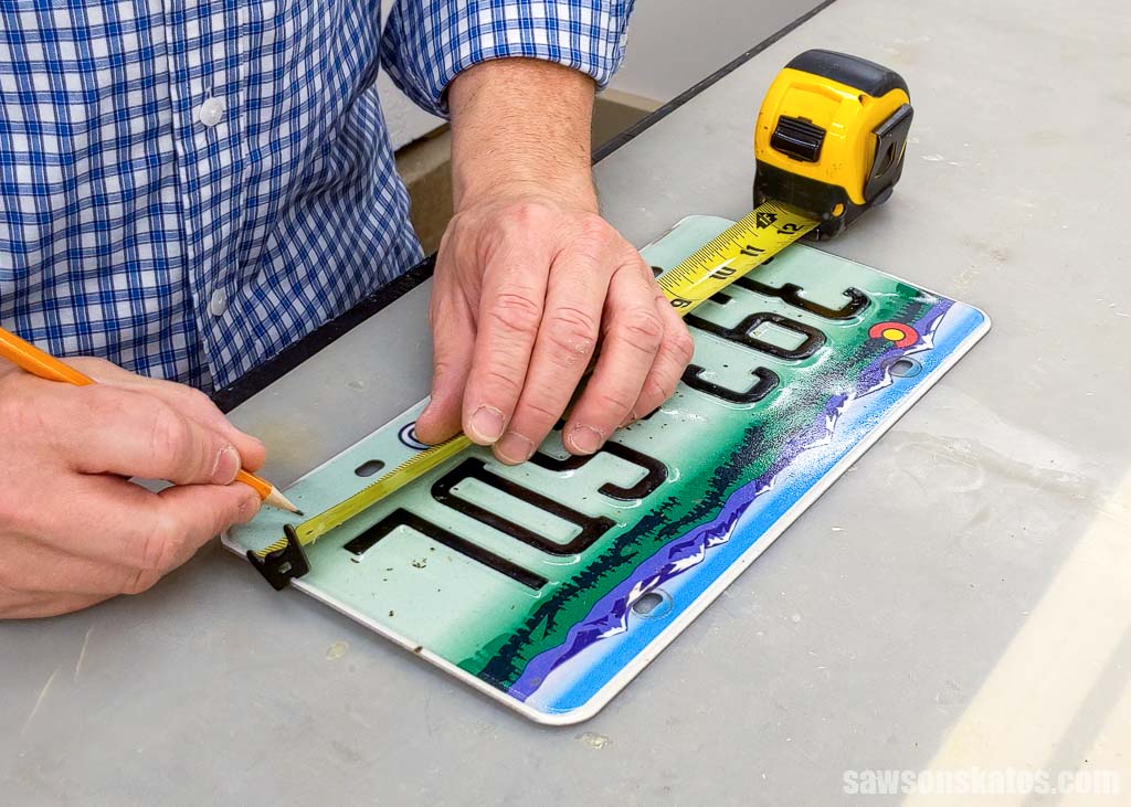 Using a pencil to mark the location for holes on a license plate