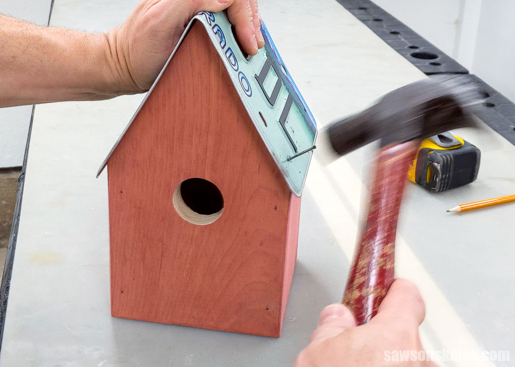 Attaching a license plate to a birdhouse with an exterior finish nail