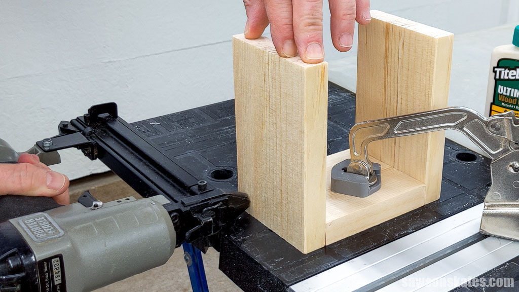 Using a brad nailer to attach the sides to the bottom of a DIY license plate birdhouse