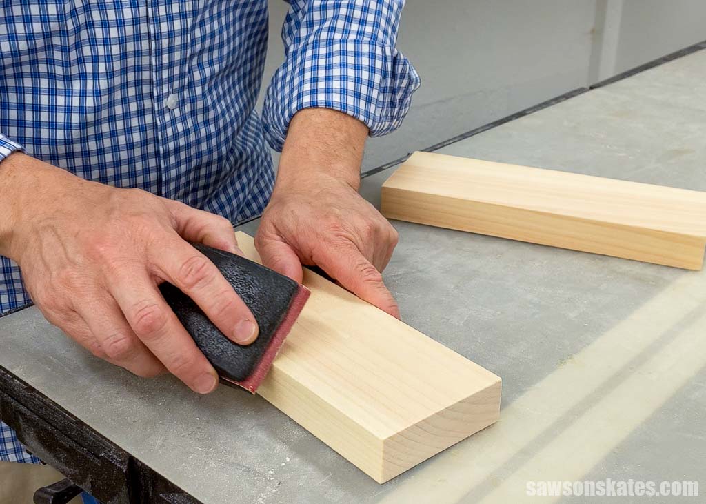 Using a sanding block to ease the edges on a piece of wood