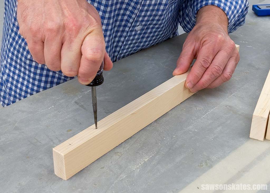 Hand pushing an awl to make a starting point for a drill bit