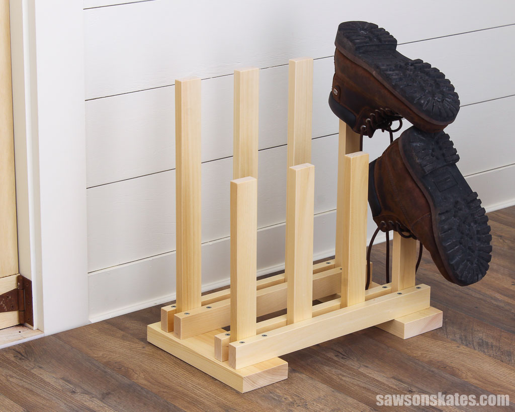 Wooden DIY boot rack on the floor with two boots on it