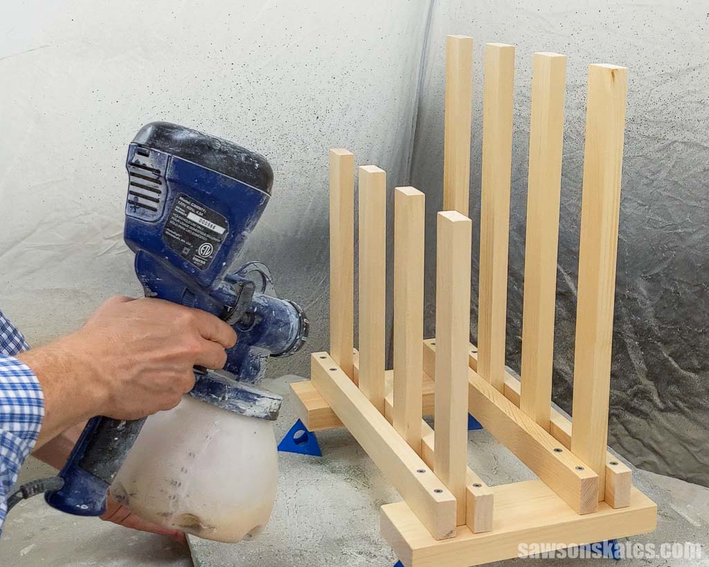 Using a paint sprayer to spray a finish on a DIY boot rack