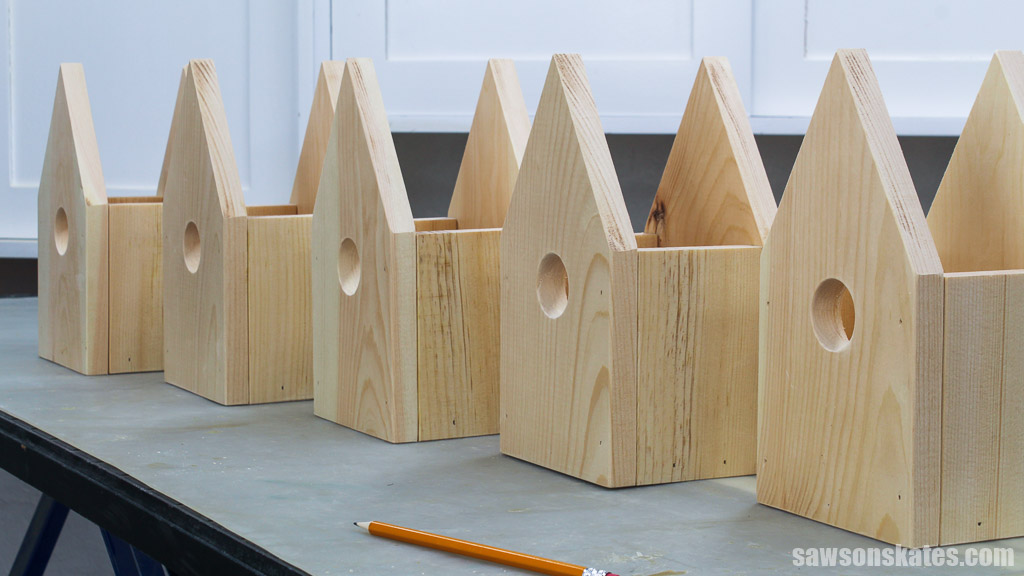 Row of unfinished DIY license plate birdhouses on a workbench