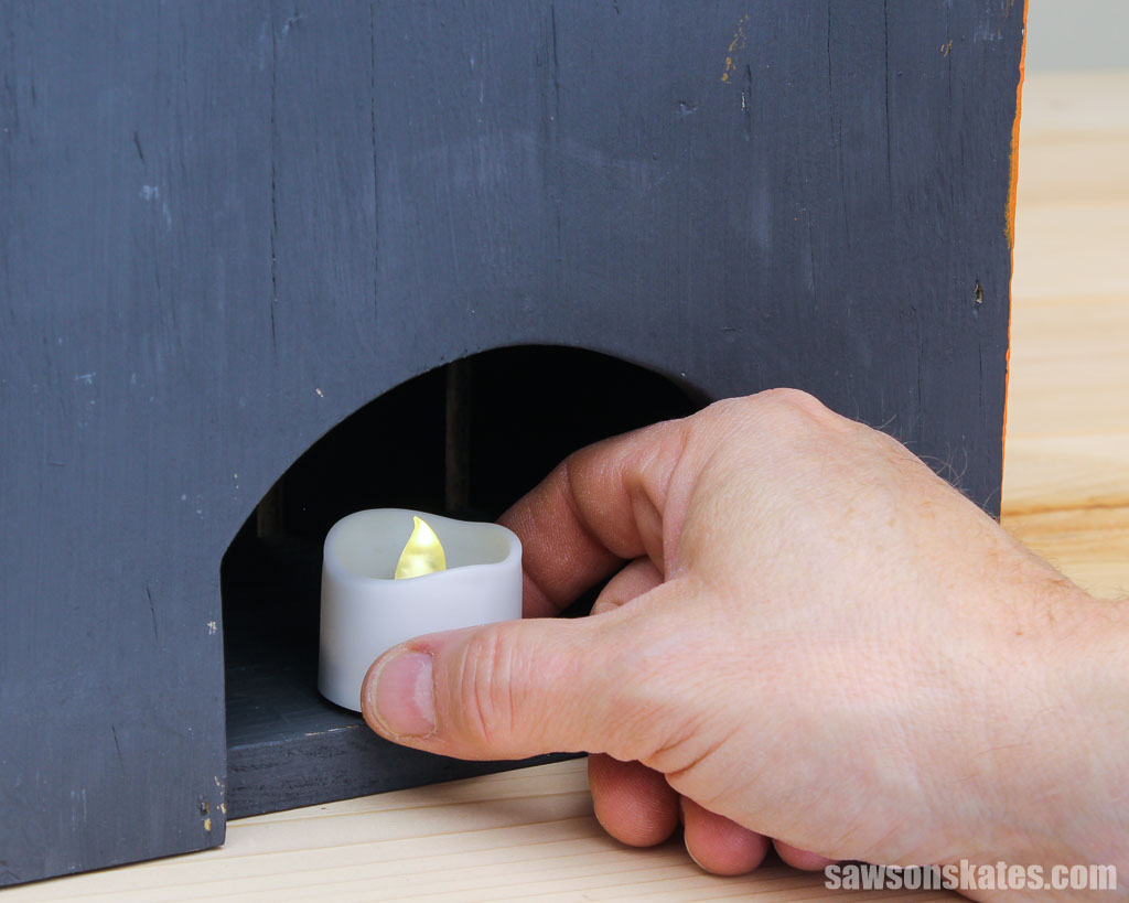 Hand placing a flameless LED tealight inside a DIY pumpkin lantern