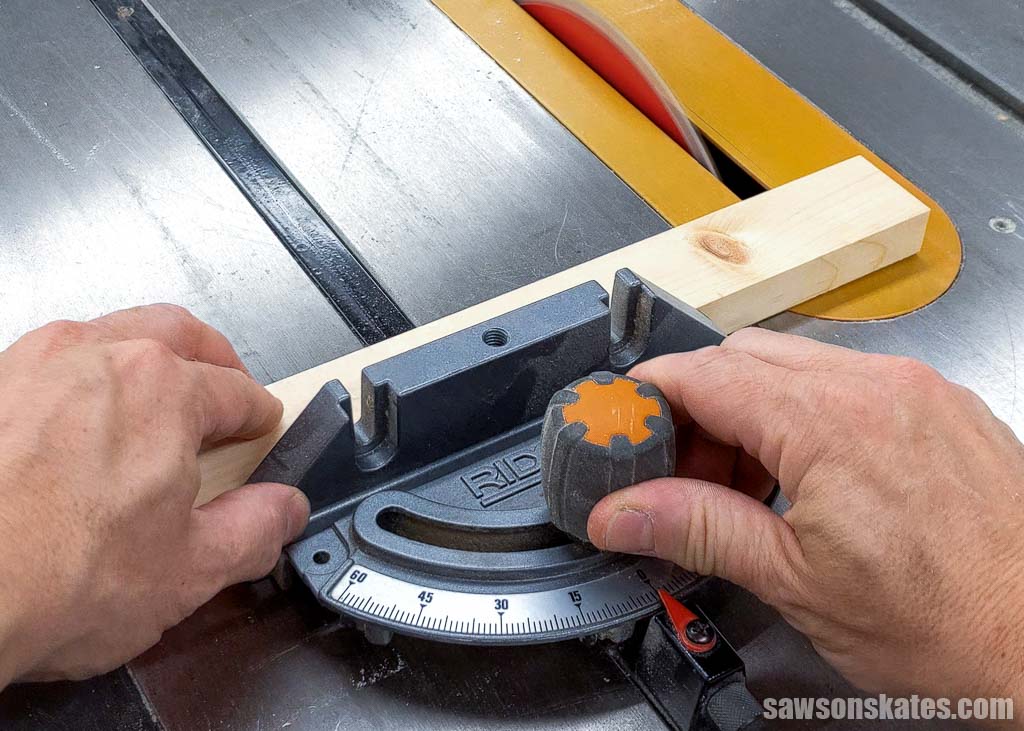Hands on a miter saw gauge guiding it through a table saw blade to make a crosscut