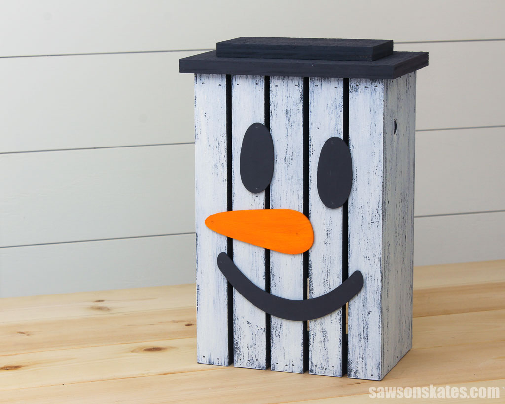 Wooden DIY snowman lantern on a table with a shiplap wall in the background