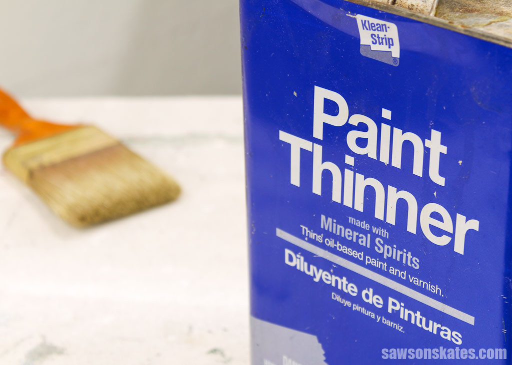 Closeup of the wording on a paint thinner container with a brush on the workbench in the background